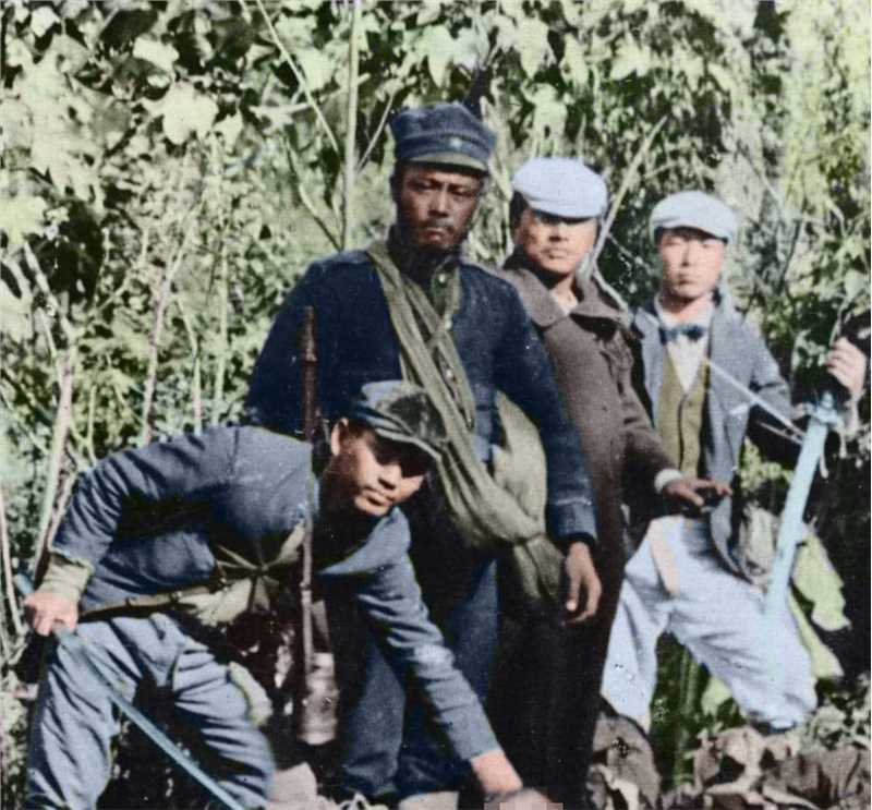 一名日军低头举着台湾人的头颅，跟旁边几位日军摆出炫耀姿态